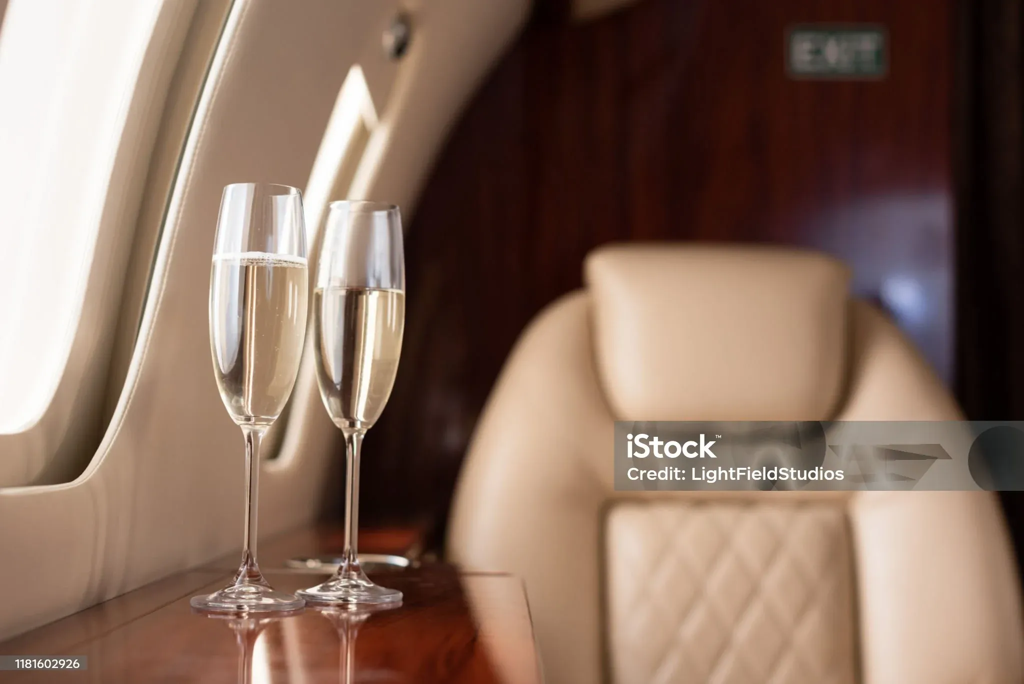Champagne glasses beside a leather jet seat