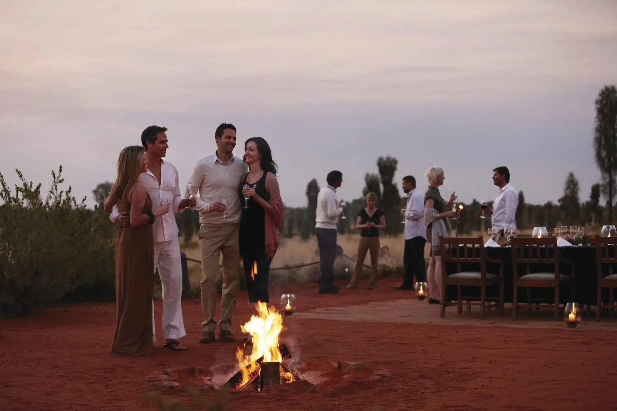 Guests dining beside a fire in the desert at dusk