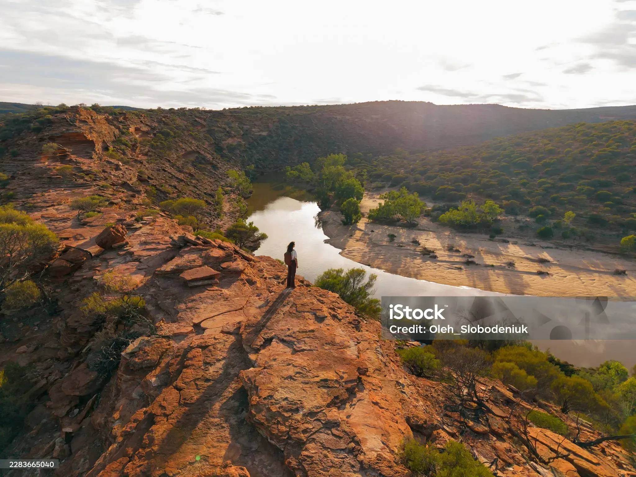 A walker on a sandstone ridge above a river gorge